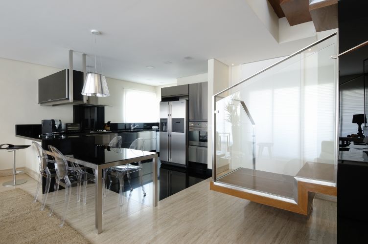 O aço escovado e o vidro, presentes na escada e na cozinha enfatizam o estilo contemporâneo do living