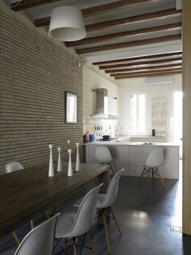 O chão do loft de 120 m² em Barcelona é revestido por uma fina camada de concreto colorido por um cinza muito escuro e luminoso. A cozinha, por sua vez, exibe janelas grandes e uma porta com painéis de vidro que se abre para um pequeno balcão voltado para a rua