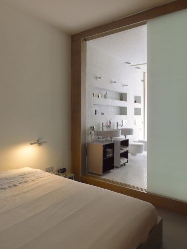 A cama do loft de Barcelona foi projetada pela empresa catalã Ylab Architectos e, no banheiro, os arquitetos optaram por um engenhoso espaço estruturado por painéis de vidro opaco e deslizante