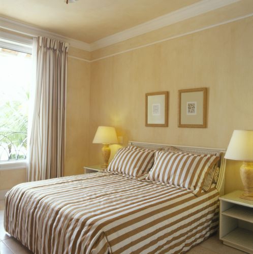 Um dos quartos de hóspedes foi decorado com tecidos em tom dourado de bege, usado na confecção de colchas, cortinas e almofadas