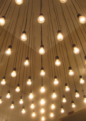 Projeto de iluminação composto por várias lâmpadas incandescentes pendentes do forro, aplicado em um hall