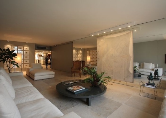 Na sala do apartamento do arquiteto David Bastos, em São Paulo, a parede espelhada recebeu uma cortina; o recurso quebra a presença do material, mas mantém suas propriedades